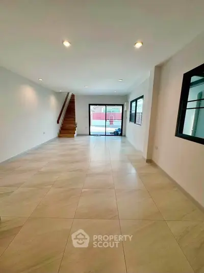 Spacious modern living room with elegant staircase and large windows