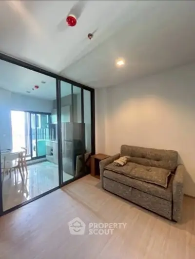 Modern apartment with glass partition and cozy sofa in bright living area.