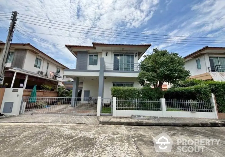 Modern two-story house with spacious front yard and lush greenery in suburban neighborhood.