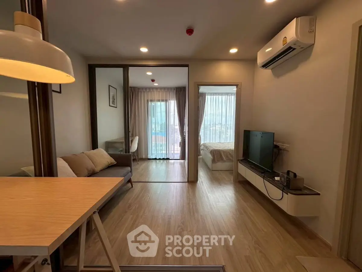 Modern apartment interior with open living room and bedroom, featuring sleek wooden flooring and stylish decor.