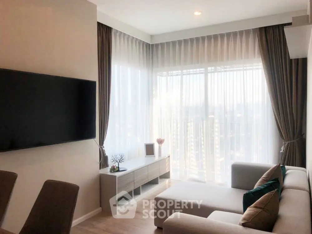 Modern living room with large windows and stylish decor in a high-rise apartment.