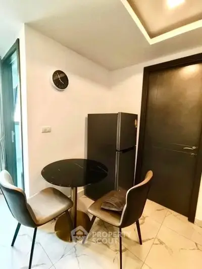 Cozy dining nook with modern chairs and sleek fridge in stylish apartment.