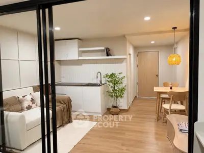 Modern open-plan living room with cozy kitchen and dining area, featuring stylish decor and warm lighting.
