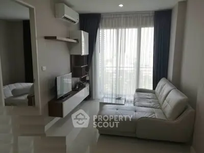 Modern living room with sleek white sofa and large window offering natural light and city view.