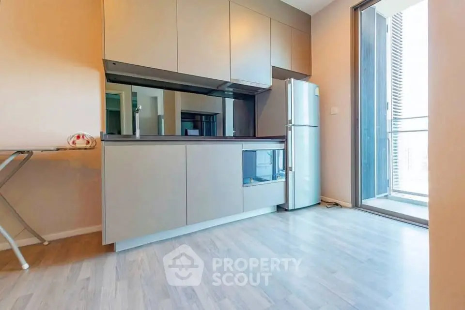 Modern kitchen with sleek cabinetry and stainless steel fridge in a bright apartment.