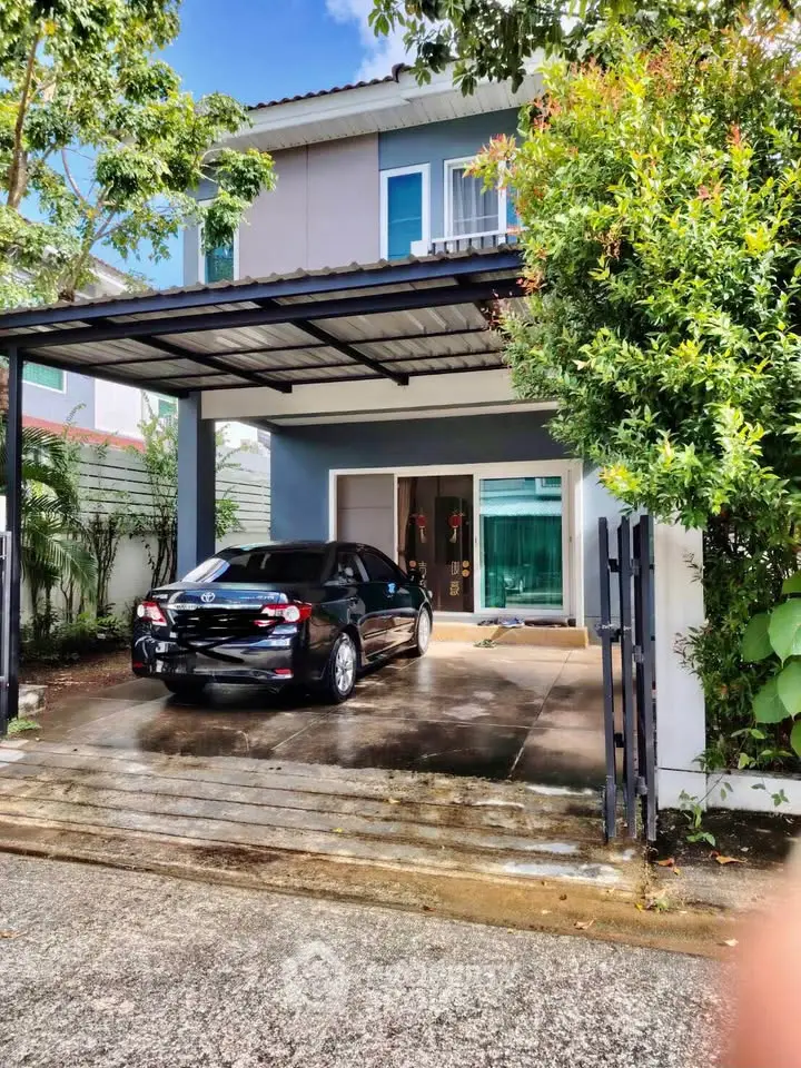 Modern two-story house with carport and lush greenery in a serene neighborhood.