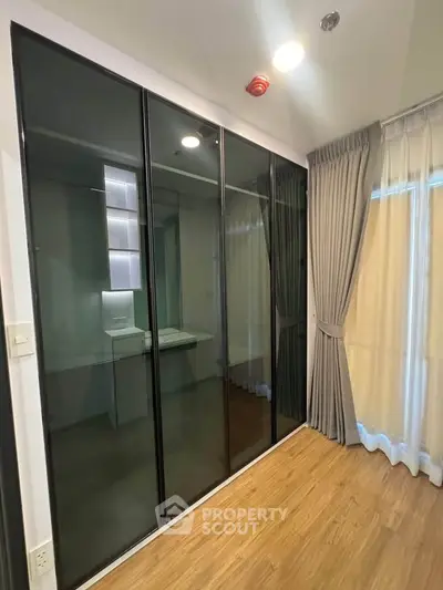 Modern bedroom with sleek glass wardrobe and elegant curtains