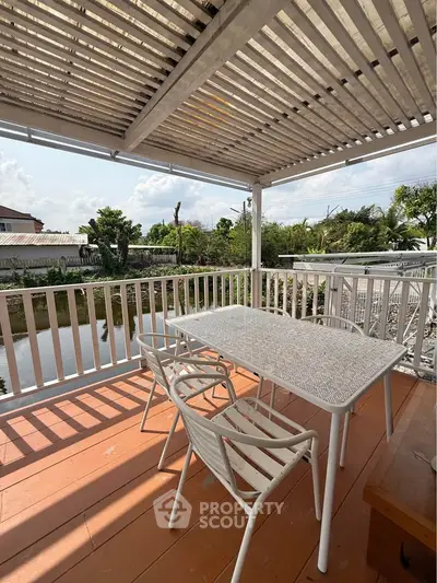 Charming outdoor balcony with stylish white furniture and scenic water view, perfect for relaxation.
