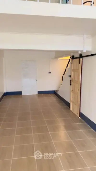 Spacious interior with tiled flooring and staircase, ideal for versatile use.