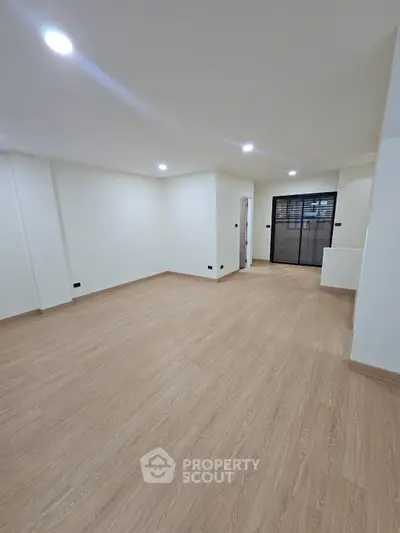 Spacious empty room with wooden flooring and modern lighting, ideal for customization.
