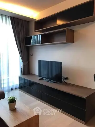 Modern living room with sleek TV stand and stylish shelving, featuring natural light and elegant decor.