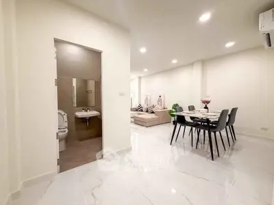 Spacious open-plan living and dining area with modern decor and adjacent bathroom.