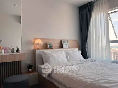 Modern bedroom with cozy bed, stylish decor, and large window offering natural light.