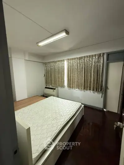 Spacious bedroom with natural light and wooden flooring