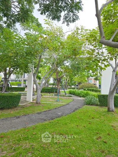Lush garden area with trees and pathway in residential complex