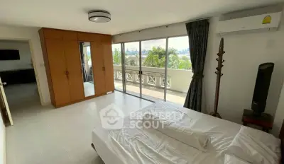 Spacious bedroom with balcony and city view, featuring modern furniture and air conditioning.