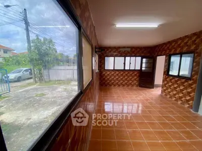 Spacious tiled room with large windows offering ample natural light and outdoor view.