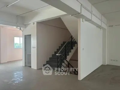 Spacious interior with modern staircase and natural light, ideal for versatile real estate opportunities.