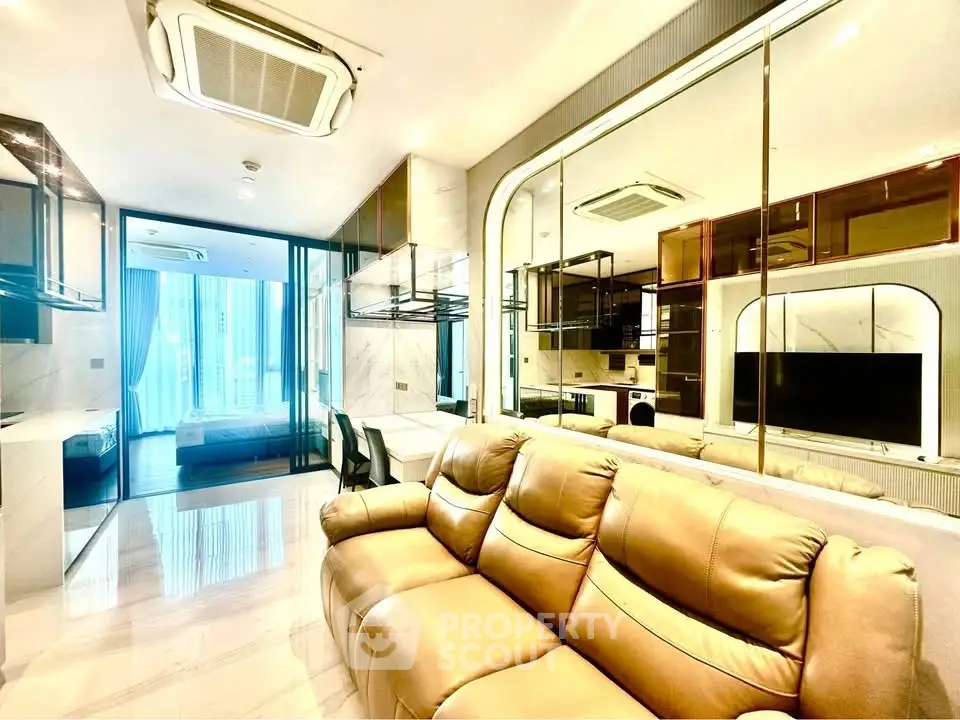 Luxurious modern living room with leather sofa and mirrored wall, featuring sleek design and ample natural light.