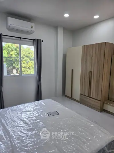 Modern bedroom with air conditioning and large wardrobe, featuring natural light and stylish decor.