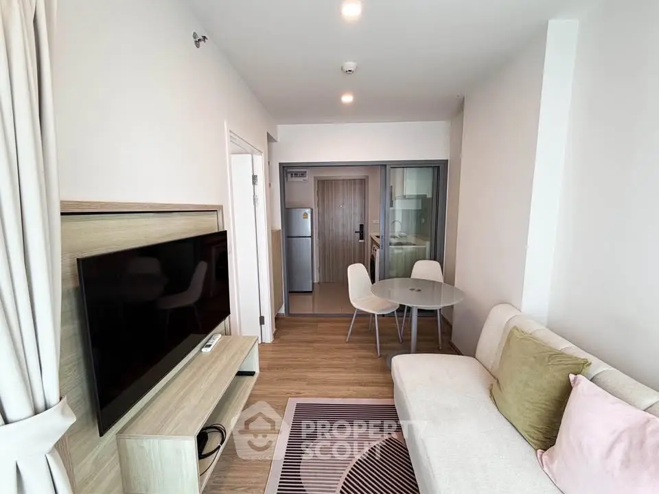 Modern living room with stylish decor and open layout, featuring a cozy sofa and flat-screen TV.