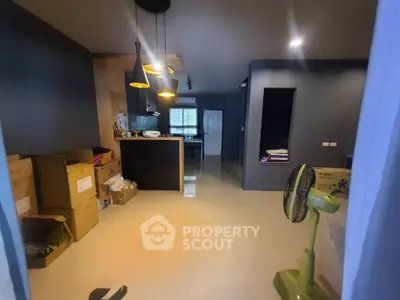 Spacious modern living area with sleek design, pendant lighting, and a cozy kitchen corner, perfect for urban living.