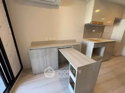 Modern kitchen with sleek cabinetry and integrated workspace in a stylish apartment.