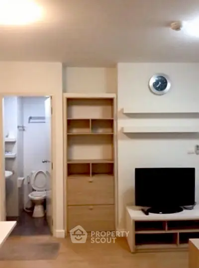 Cozy apartment interior with TV, shelves, and bathroom access