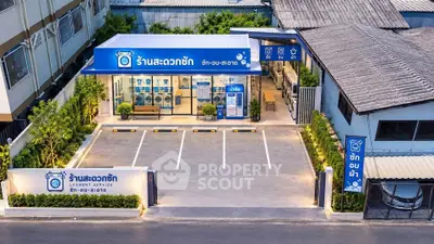 Modern laundry service building with parking and clear signage in urban setting.