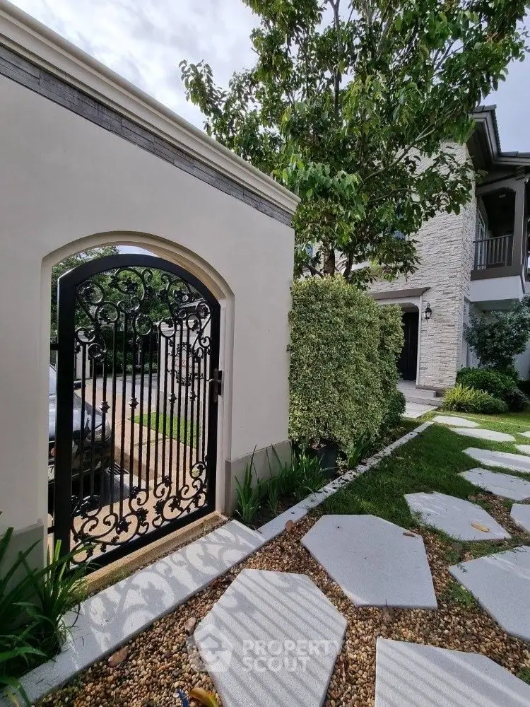 Charming garden entrance with elegant wrought iron gate and lush greenery