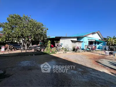 Charming rural home with spacious yard and vibrant blue roof under clear skies.