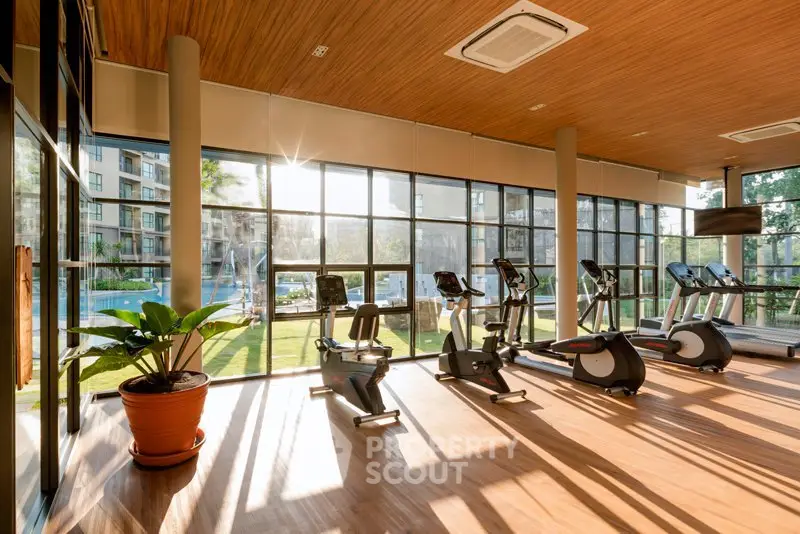 Spacious gym with modern equipment and large windows offering a scenic view, perfect for fitness enthusiasts.