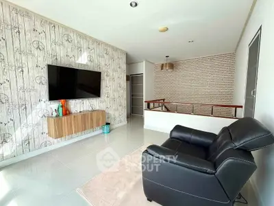 Modern living room with stylish decor and mounted TV, featuring sleek black leather chair and wooden accents.