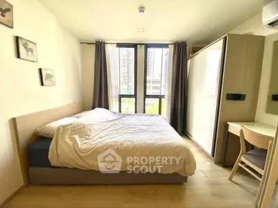 Bright and cozy bedroom with modern furnishings and large window view in urban apartment.
