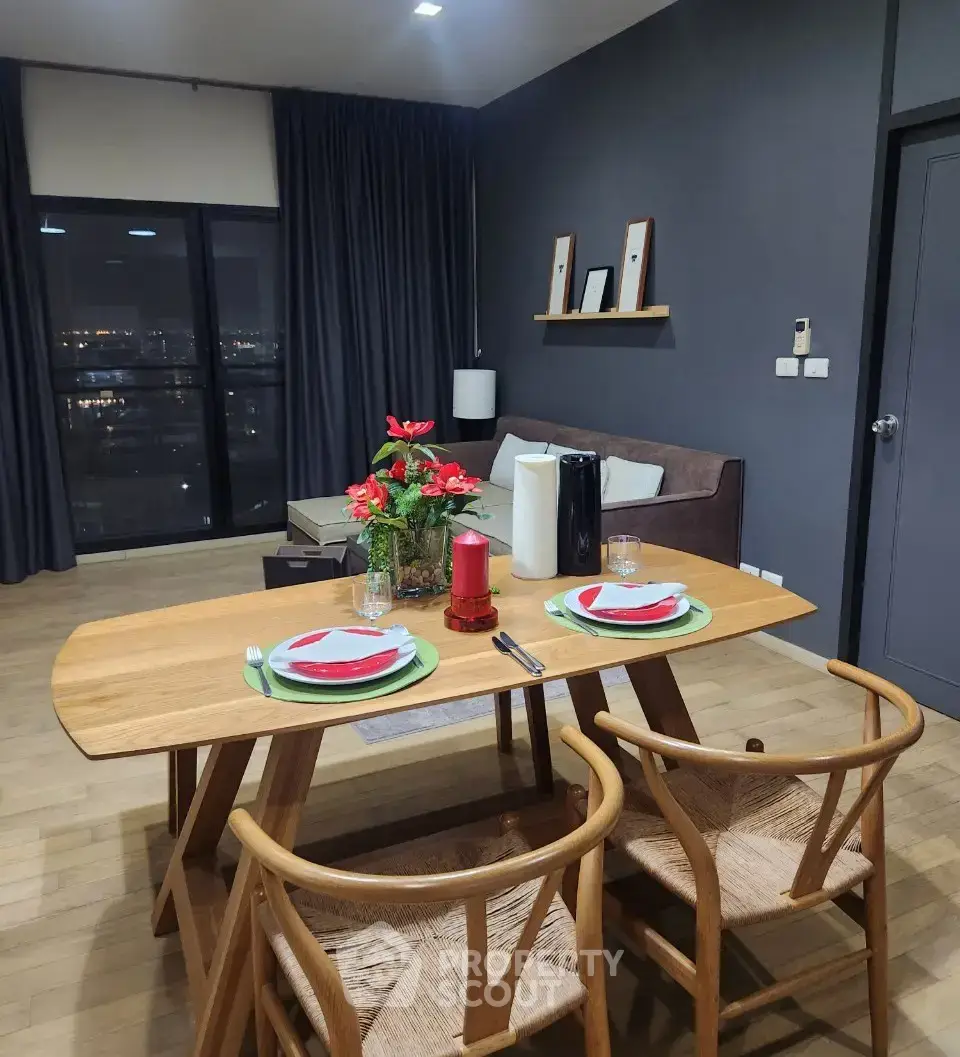 Modern dining area with wooden table and chairs, cozy living space, and city view through large window.