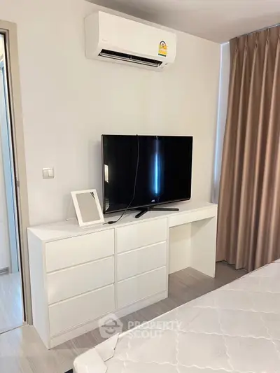Modern bedroom with sleek white furniture and wall-mounted air conditioner.