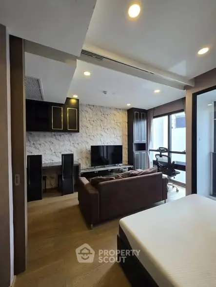 Modern living room with stylish decor and large TV, featuring a cozy sofa and natural light.