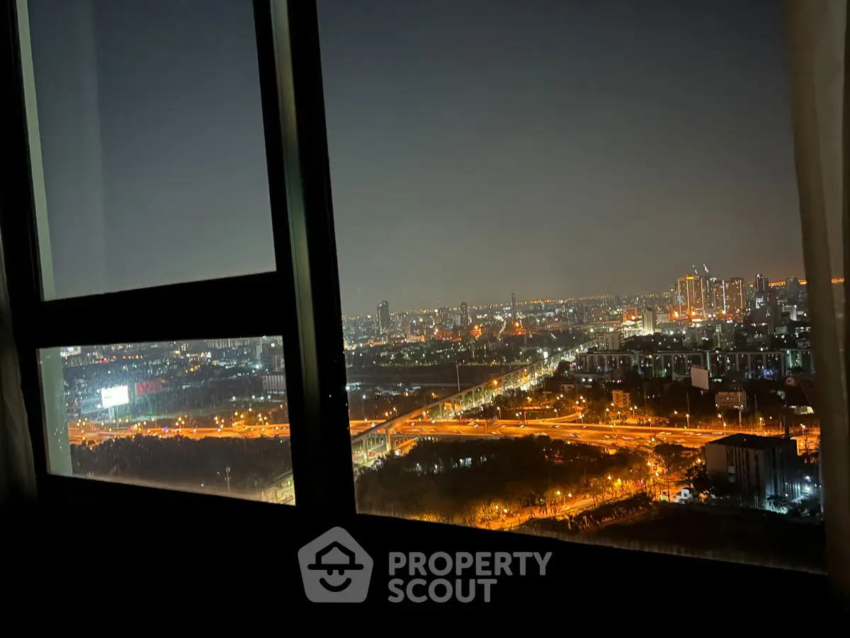 Stunning cityscape view from high-rise window at night, showcasing vibrant urban lights.