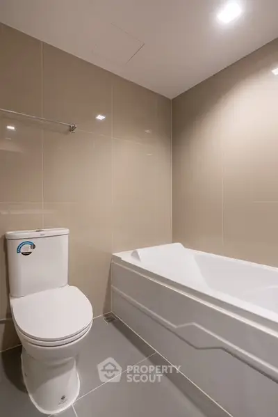 Modern bathroom with sleek bathtub and beige tiled walls