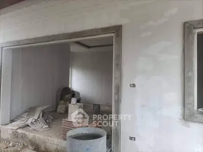 Under-construction home interior with unfinished walls and construction materials.