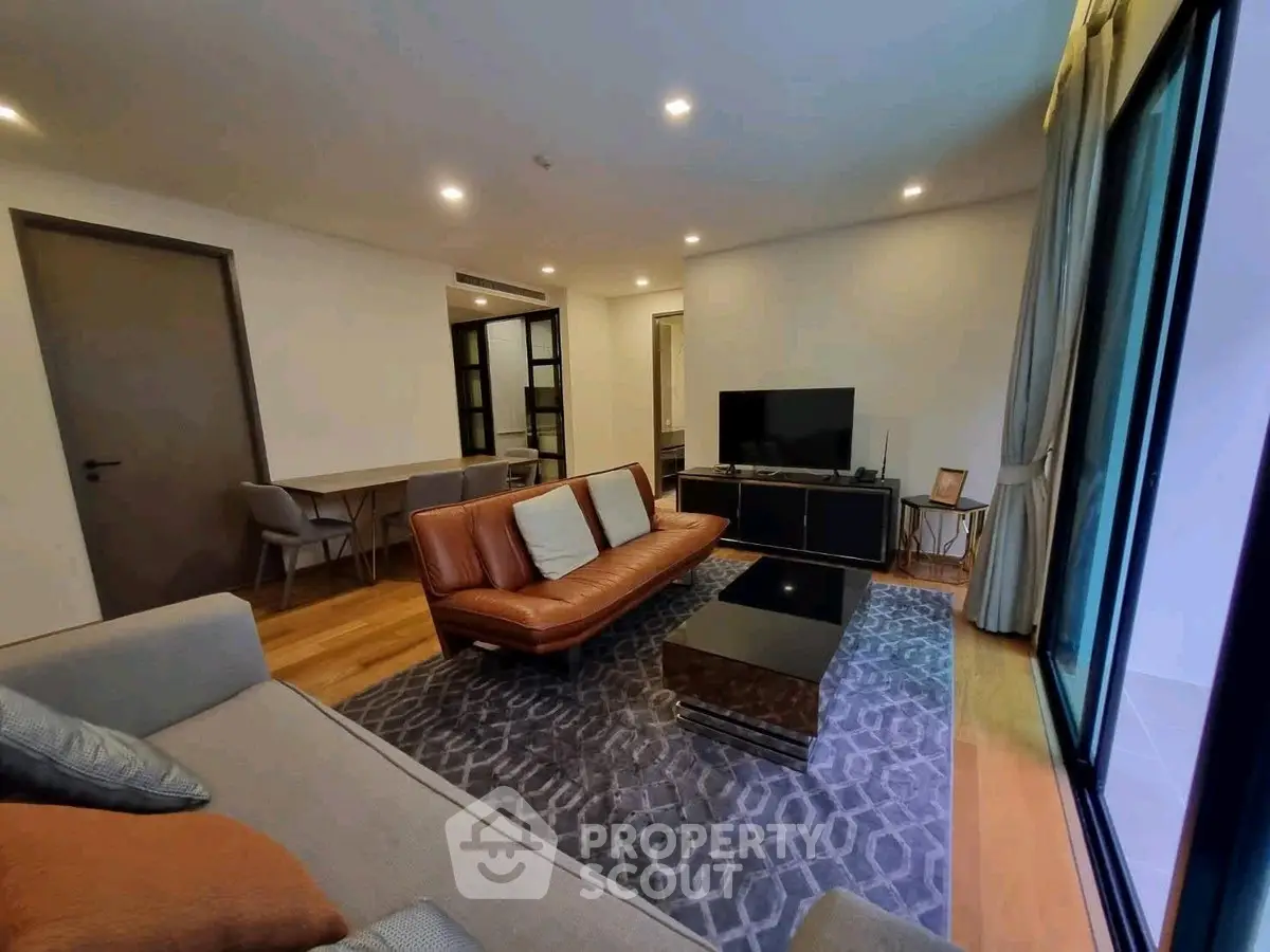 Modern living room with stylish furniture and large window offering natural light.