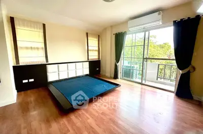 Spacious bedroom with wooden flooring and balcony access