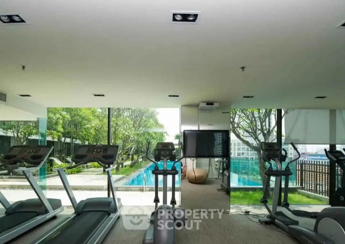 Luxurious gym with modern equipment and pool view in upscale residential complex.