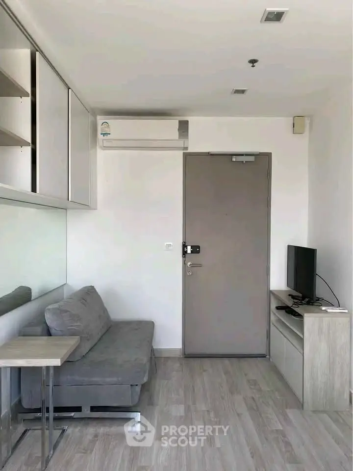 Modern compact living room with sleek furniture and air conditioning in a stylish apartment.