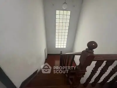 Elegant staircase with wooden railing and large window in a modern home
