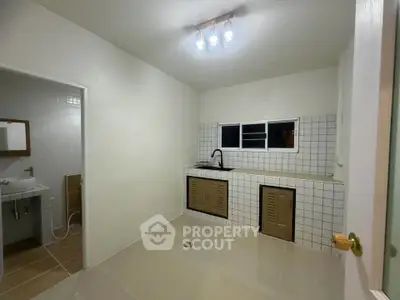 Spacious kitchen with tiled backsplash and modern fixtures, adjacent to a bathroom.