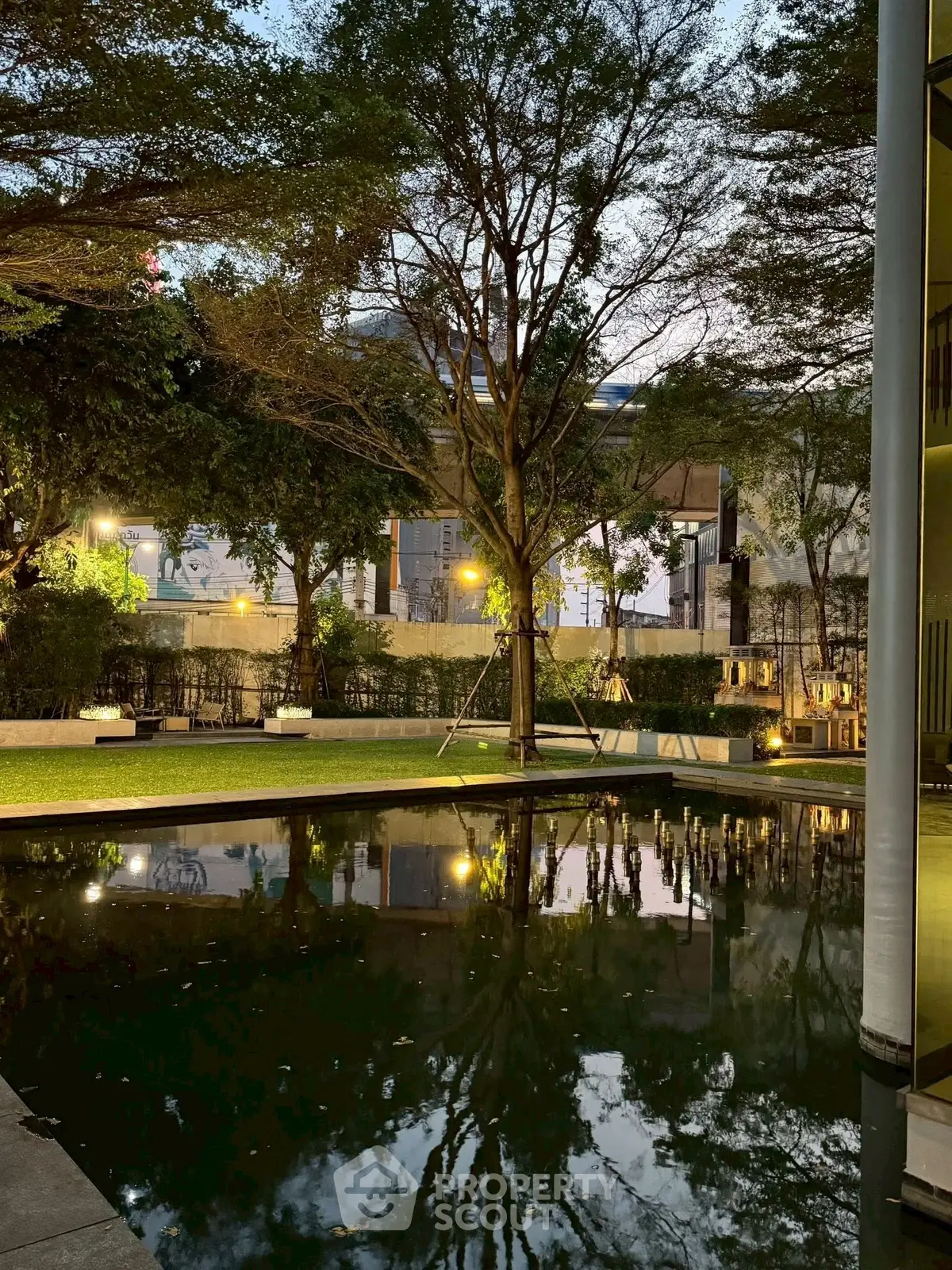 Serene garden view with reflective pond and lush trees at dusk, perfect for tranquil living.