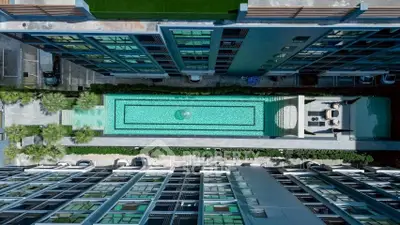 Stunning aerial view of modern apartment complex with luxurious swimming pool and lush greenery.