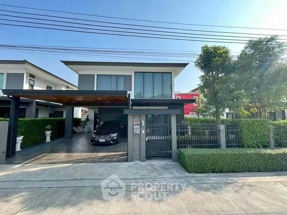 Modern two-story house with carport and lush greenery in a serene neighborhood.