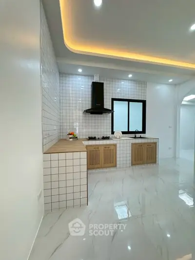 Modern kitchen with sleek design, featuring tiled walls, built-in gas stove, and elegant lighting.